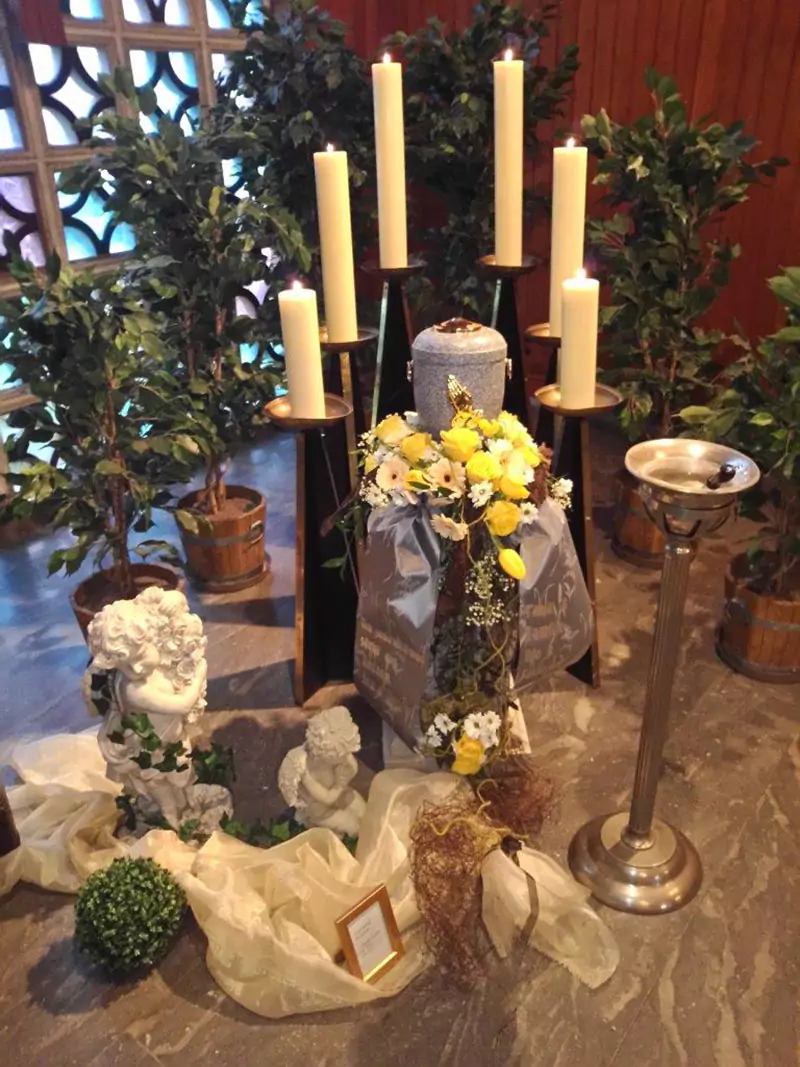 Urne mit Kerzen und Blumenschmuck
