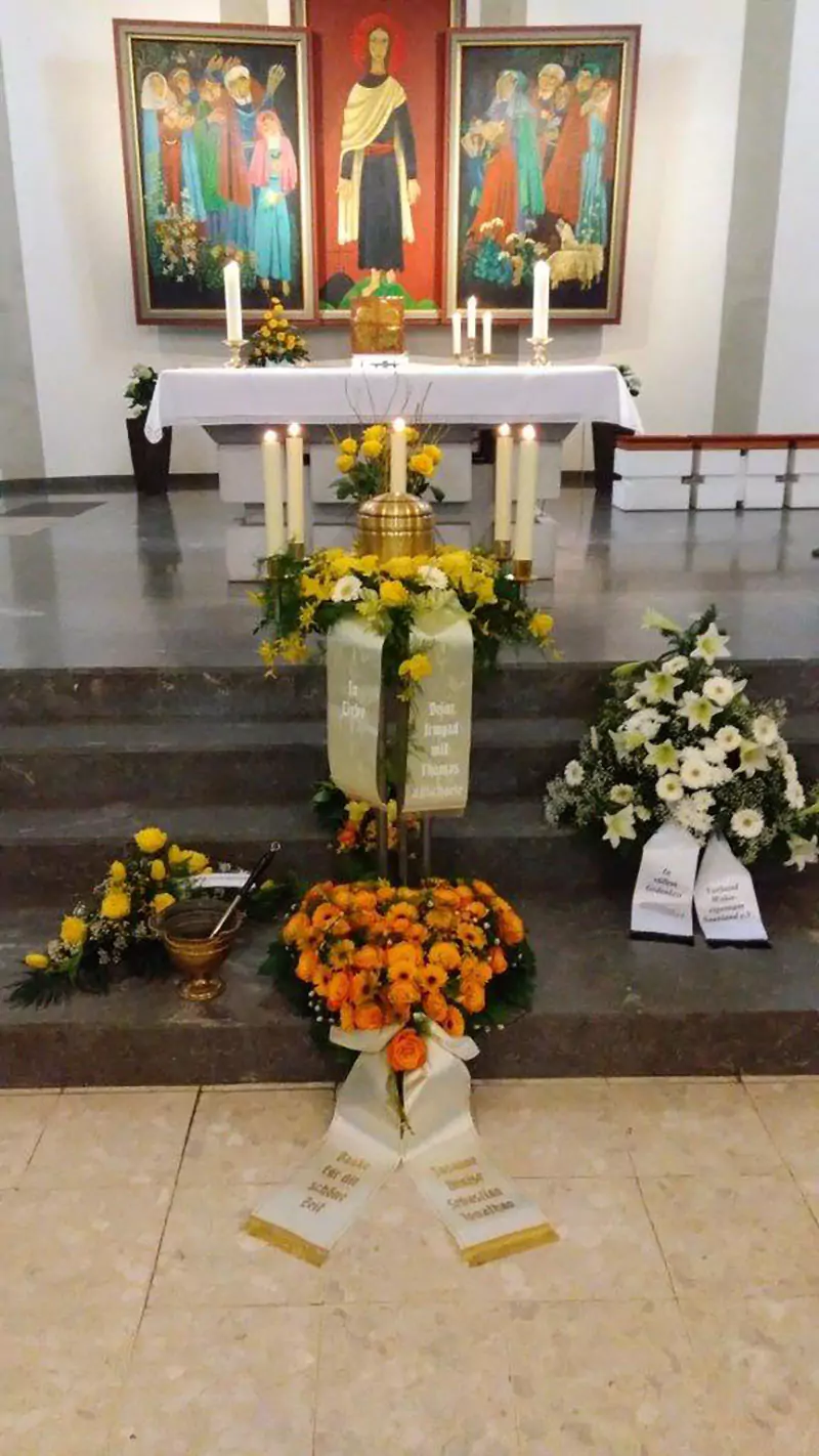 Urne mit Blumenschmuck vor einem Altar